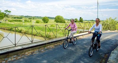 Dos mujeres cruzando en bicicleta el puente sobre el Canal du Midi